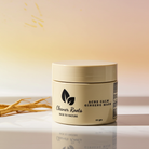 Jar of 'Acne Calm Ginseng Mask' by 'Cleaner Roots' on a reflective surface with a blurred natural background.